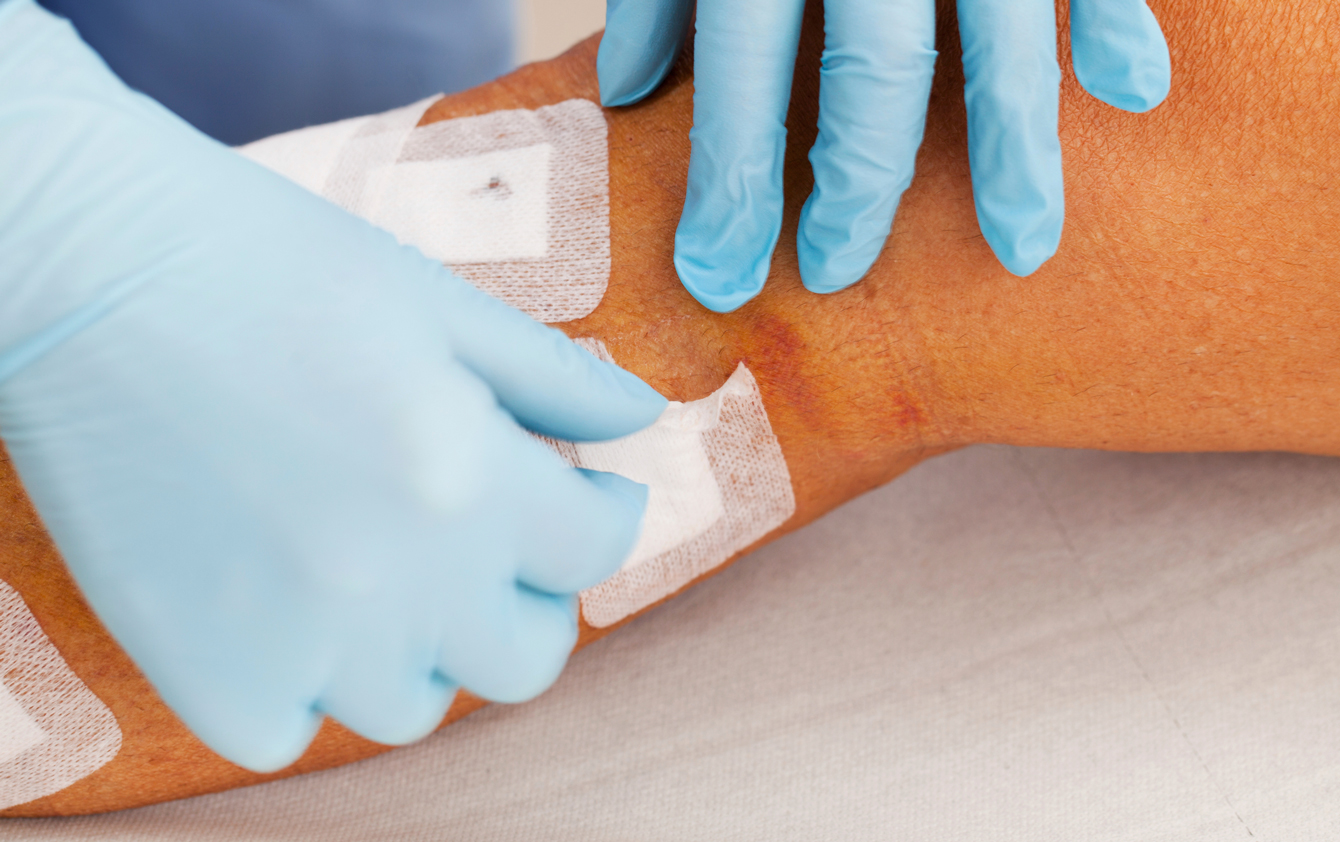Gloved hands applying a bandage to a leg