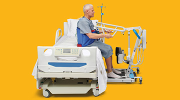 Male patient sitting up in hospital bed with assist from a patient lift