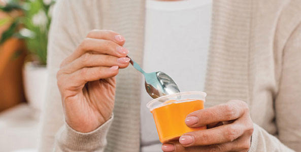 STK_Woman-eating-Gelatein Hands holding a nutition cup with spoon