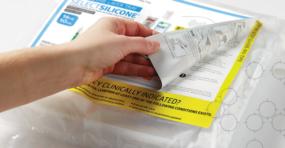 Hand peeling back label on an indwelling urinary catheter tray with patterned background Hand peeling back label on an indwelling urinary catheter tray with patterned background