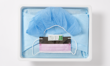 SKU_STCBC01US_CVC Kit Replica_052_RGB 1 Blue surgeon's gown, mesh bouffant cap, pink face mask and hand sanitizer packet in a white tray