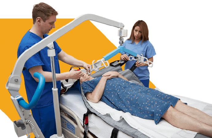Two attendants in blue scrubs assisting patient in sitting with mobility