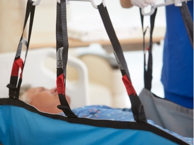 Caregiver using a sling and lift to transfer a patient