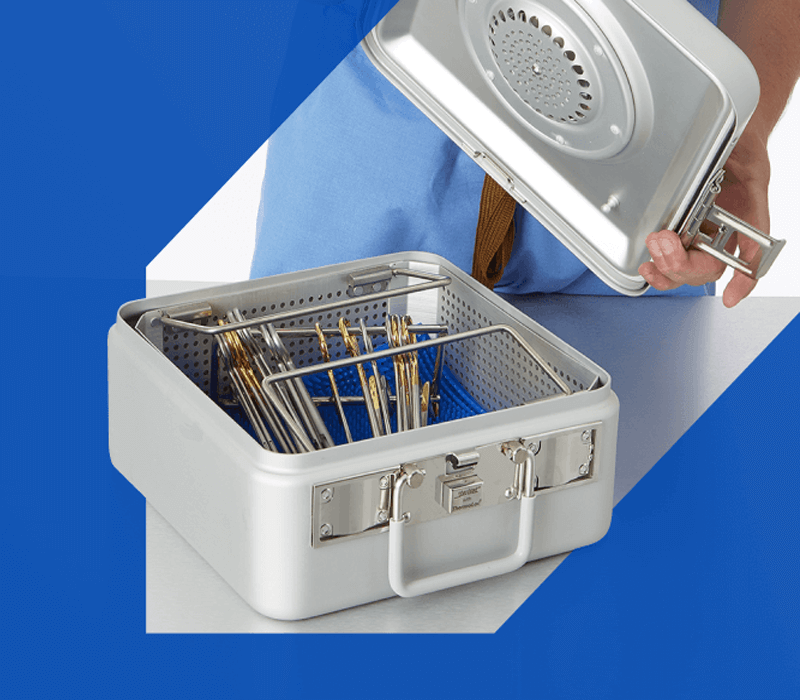 Surgical instrument set inside a sterilization container, with an SPD worker holding the lid in the background
