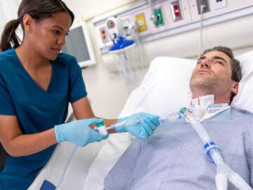 Female clinician suctions a male patient’s endotracheal tube using the ClearPro Closed Suction System