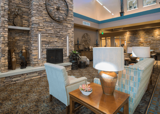 A lobby with a large stone fireplace, chair and couches