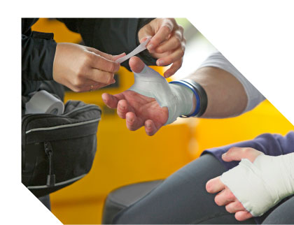 Sports caregiver using athletic tape to wrap the wrist and thumb of an athlete