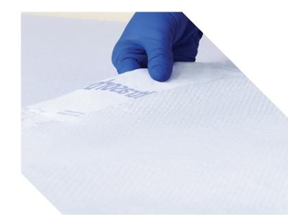 Gloved caregiver laying an Ultrasorbs on a bed