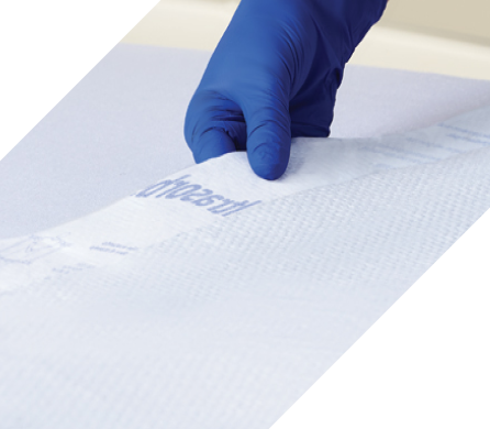 Gloved caregiver laying an Ultrasorbs on a bed