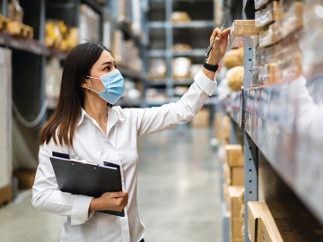 Woman wearing mask checks medical supply inventory levels in a warehouse