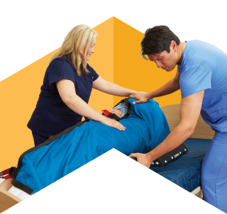 Two attendants in blue scrubs turning a patient.