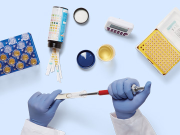 broad-lab-portfolio Collection of different lab supplies with gloved clinician hands injecting a sample into a test tube