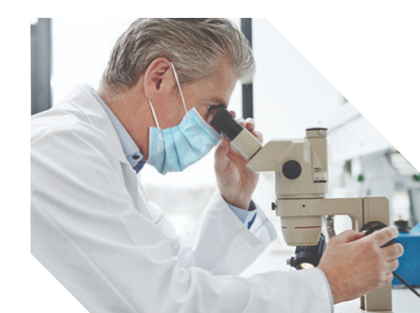 Masked clinician looking into a microscope