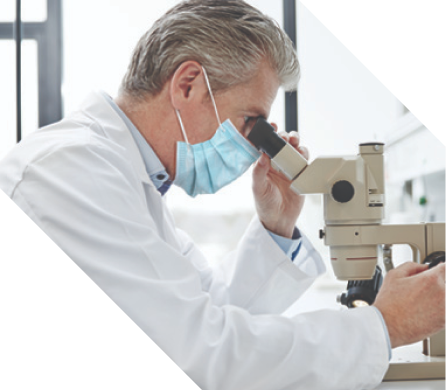 lab-distribution Masked clinician looking into a microscope