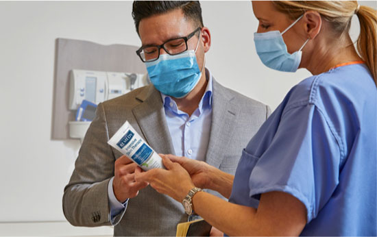 pressure-injuries Masked Skin Health specialist shows a masked caregiver a skin care product