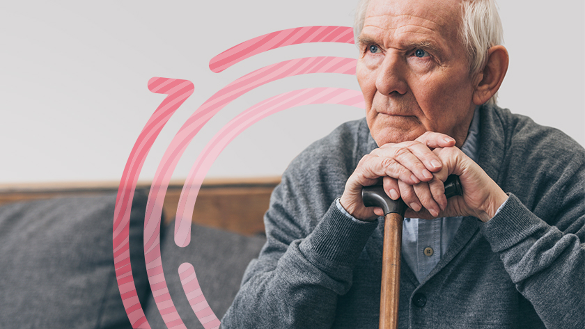 Elderly man rests his hands on top of his cane in front of him