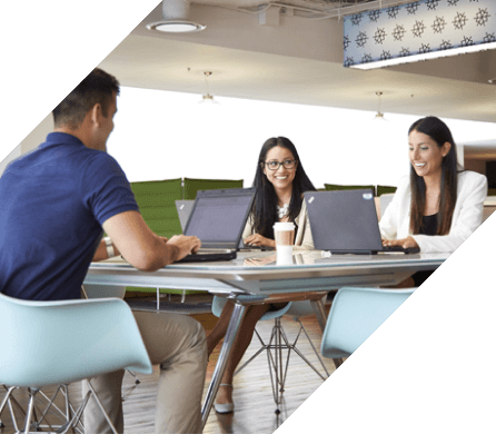 Two women and a man meeting at a conference table with open laptops