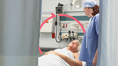 Clinician standing at bedside of older male patient in hospital