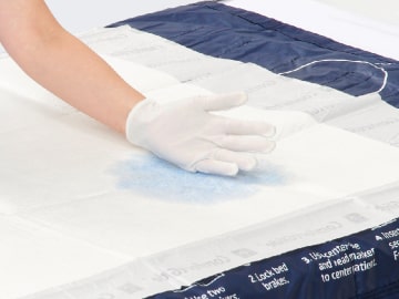 fight-skin-4-min Caregiver’s gloved hand touching drypad that has absorbed fluid