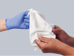 improves-comfort Caregiver’s gloved hand placing moisture wicking fabric for skinfolds in patient’s hands