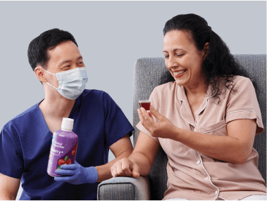 Clinician observes patient drinking medicine cup with special medical cranberry product