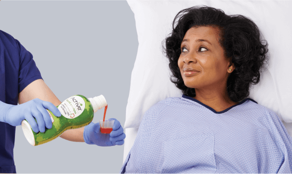 Clinician’s gloved hand offering specialized nutrition product to patient in hospital room