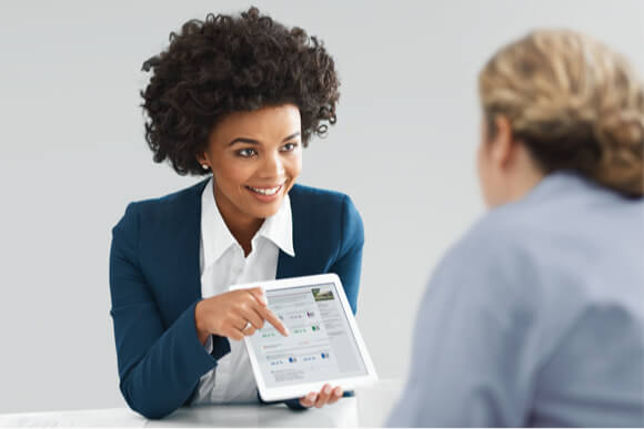 Female director of a skilled nursing facility uses a tablet to share quality data with a female IDN administrator