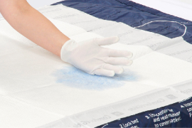 Meta Gloved caregiver hands dispense ISP antifungal powder to patient’s foot.