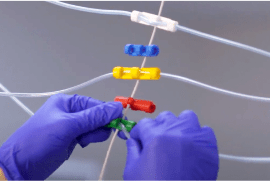 innovation-stratergies-2-min Two gloved hands fastening a plastic clip onto IV line