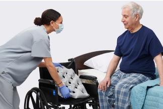 caregiver assisting a resident from bed to a wheelchair