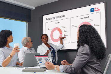 Man pointing to chart on a screen in a conference room of people