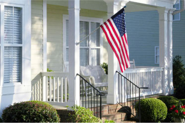 Front porch of a house with the American flag hanging from a pole.