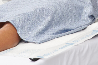 Clinician positions an underpad, a type of incontinence product, on a table