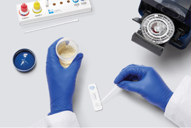 Gloved hands take a lab test sample on a tabletop with several physican office lab devices.
