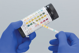 Gloved hands hold a CLIA-waived testing kit..