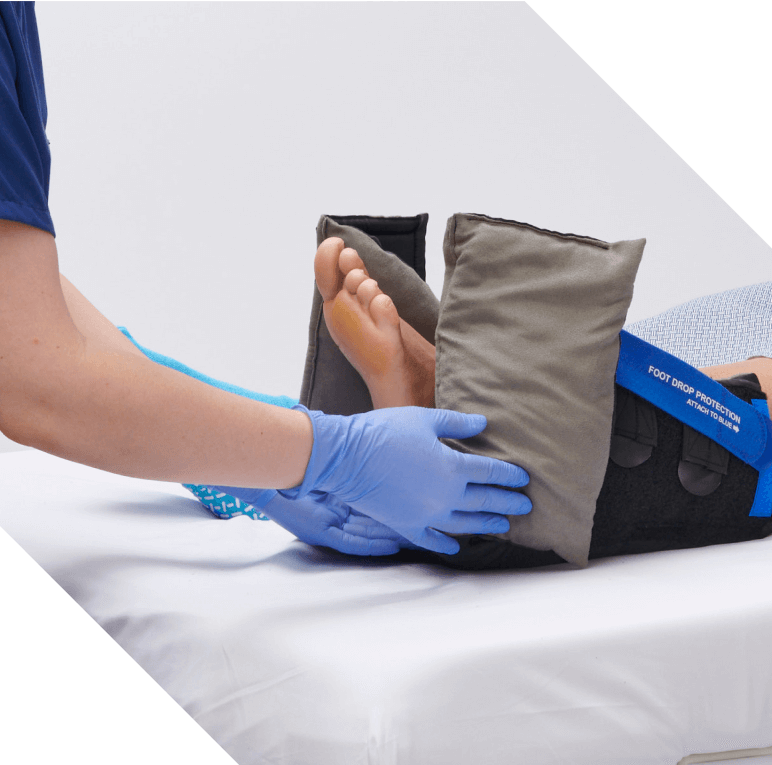 Caregiver’s gloved hands securing a foot drop protection strap on HeelMedix Advanced as it’s applied to patient’s foot