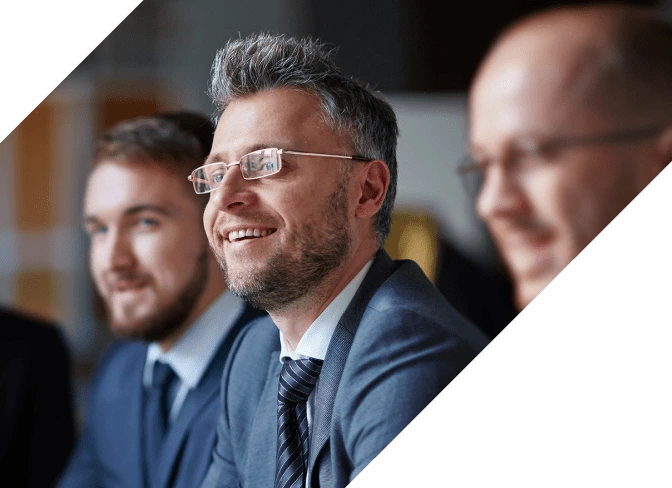 Executives smiling and listening to a speaker.