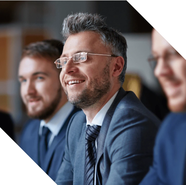 Executives smiling and listening to a speaker.