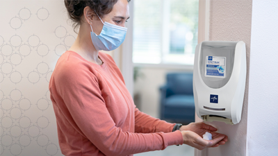 Visitor receiving hand sanitizer at dispenser
