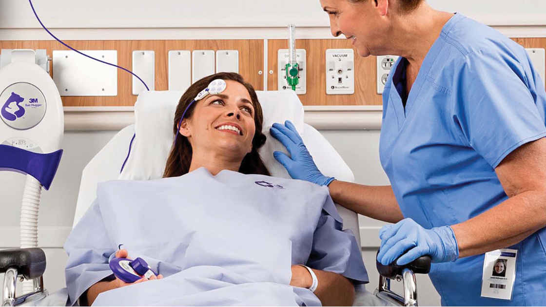 Clinician tends to a reclined patient wearing a surgical warming gown