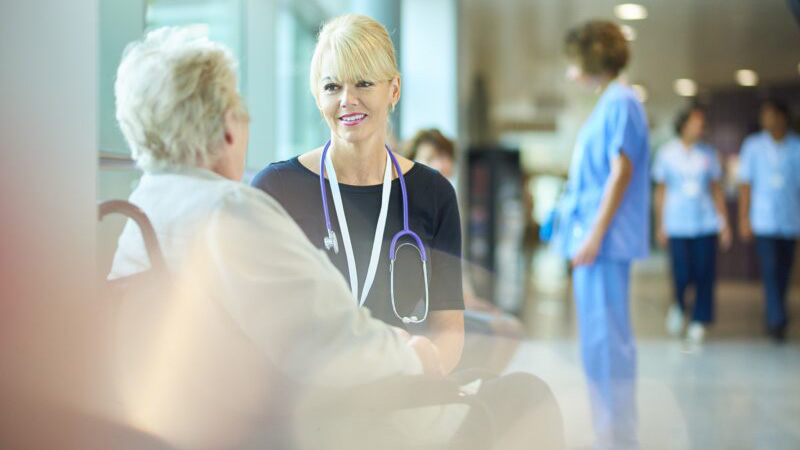 Clinician speaks with woman seated in a wheelchair in at Advanced Pain Care