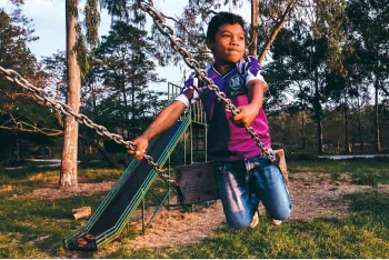 Young child swinging at a playground outside.