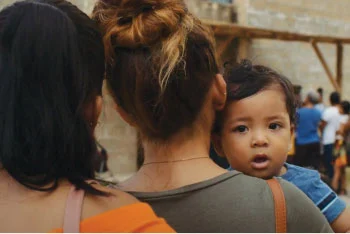 Close-up of two women facing away from camera holding child facing camera