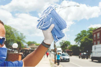 Close-up of volunteer holding masks to hand out outside in a community.