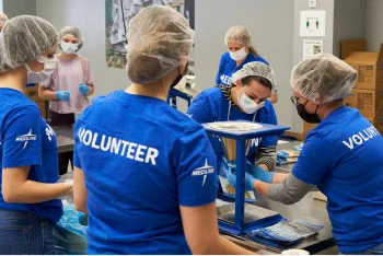 Medline volunteers in healthcare setting dressed wearing OR hair nets and masks.