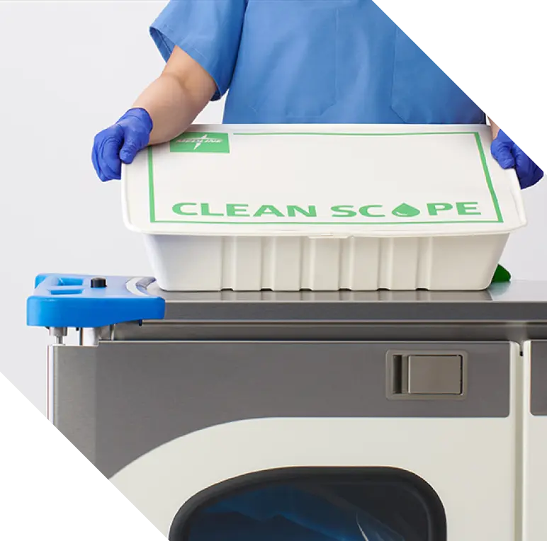 Gloved employee in blue scrubs holding environmentally friendly Clean Scope box.