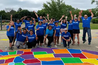 healthcare-sustainable Group of people wearing blue tshirts gathered around a color-coded map of US