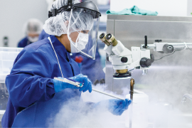 renewal_medical_devices_reprocessing Woman working in lab wearing protective facial equipment, blue scrubs and gloves