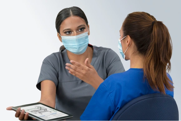 Two clinicians discussing illustration of patient with Foley catheter on tablet