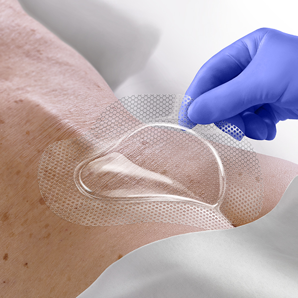 STK_Optiview_Secrum_in-us_blue_RGB Clinician's gloved hand applies OptiView to elderly patient's sacral area